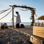 Mariage à la plage : arche sur le sable avec rubans et préparatifs